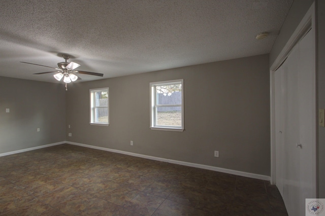 empty room with ceiling fan and a textured ceiling