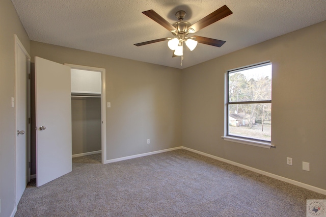 unfurnished bedroom with a textured ceiling, light colored carpet, a closet, and ceiling fan