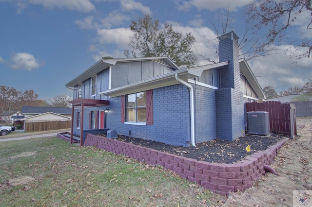 view of side of home with a yard and central AC