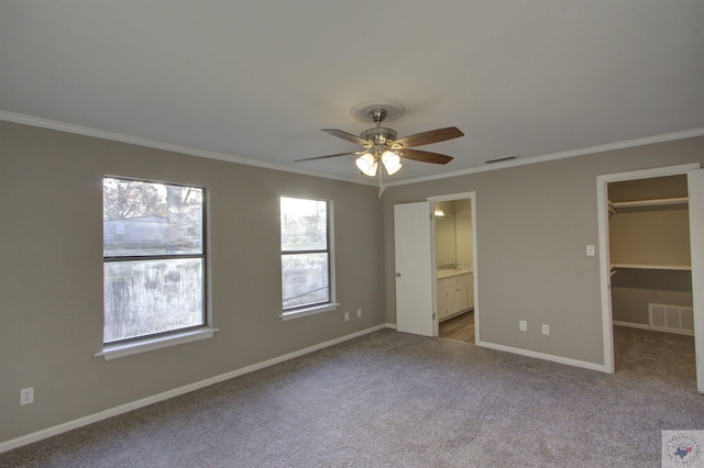 unfurnished bedroom featuring a walk in closet, connected bathroom, light carpet, a closet, and ceiling fan