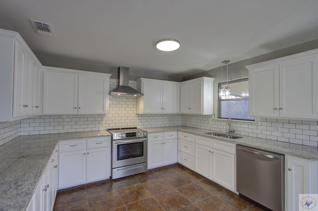 kitchen with appliances with stainless steel finishes, white cabinets, wall chimney range hood, decorative backsplash, and sink