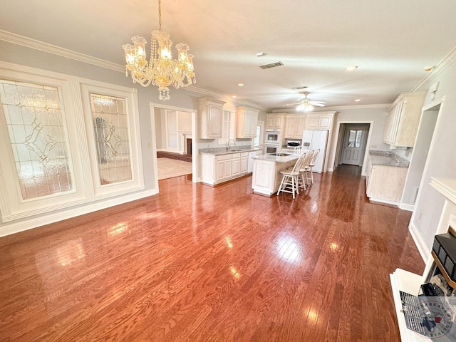 kitchen with white appliances, decorative light fixtures, an island with sink, sink, and a breakfast bar area