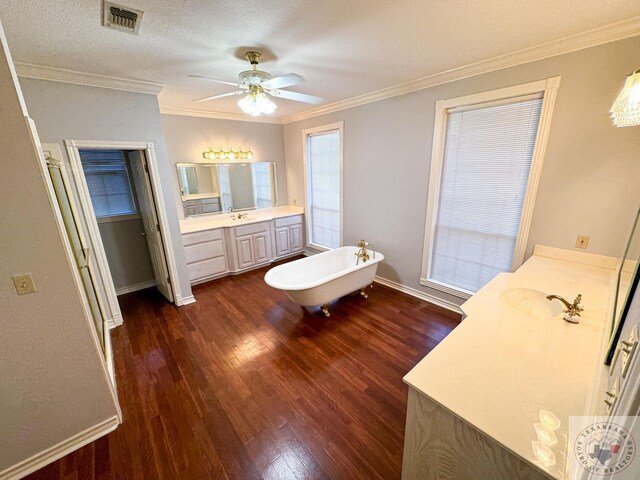 bathroom with a textured ceiling, vanity, a tub, hardwood / wood-style flooring, and crown molding