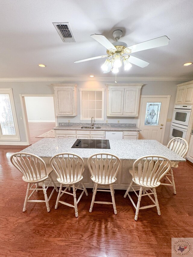 kitchen with crown molding, a breakfast bar area, and light stone counters