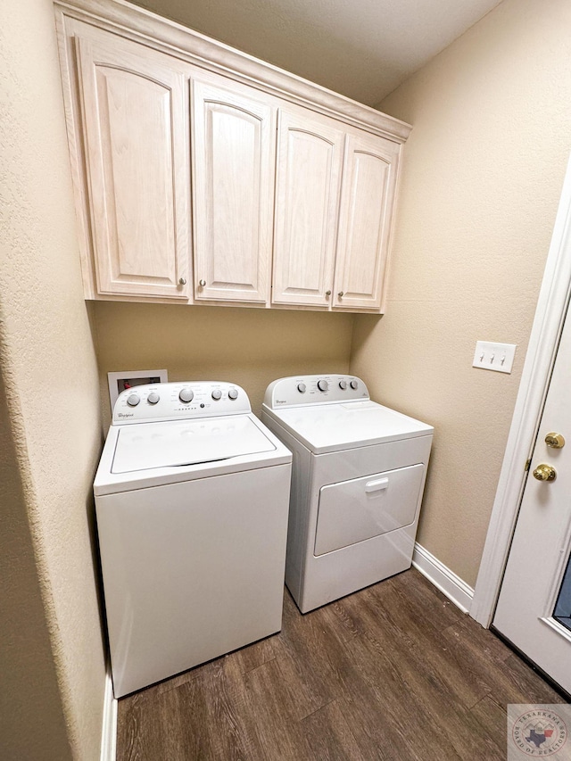 laundry area featuring washing machine and clothes dryer, dark wood-type flooring, and cabinets