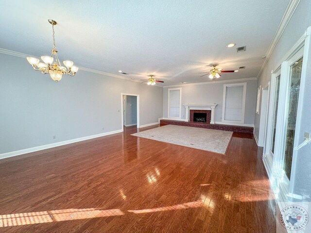 unfurnished living room with a fireplace, a textured ceiling, ornamental molding, ceiling fan with notable chandelier, and dark hardwood / wood-style floors