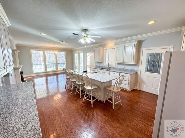 dining space featuring dark wood-type flooring, sink, a textured ceiling, and crown molding