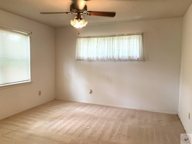 empty room featuring ceiling fan, a textured ceiling, and carpet