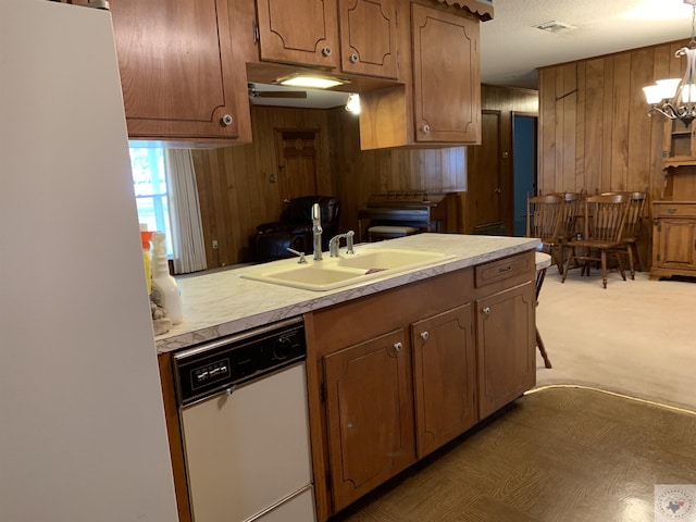 kitchen featuring brown cabinetry, a sink, light countertops, and white dishwasher