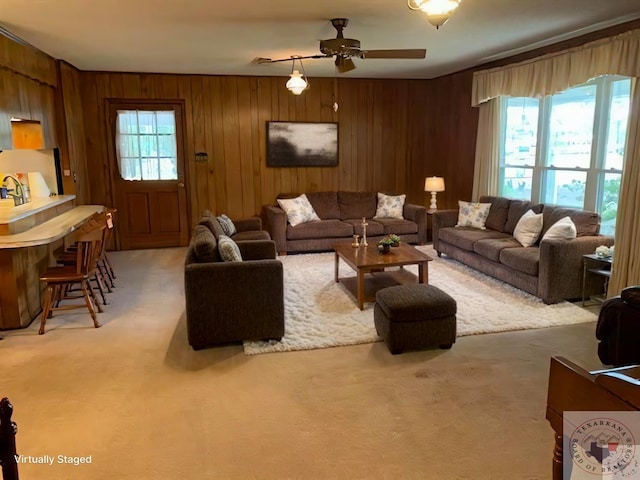 living area featuring ceiling fan, light carpet, and wood walls