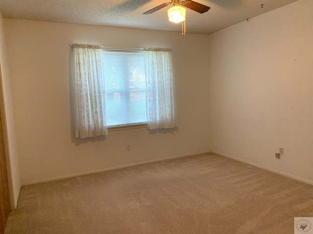 spare room featuring baseboards, light carpet, a textured ceiling, and ceiling fan