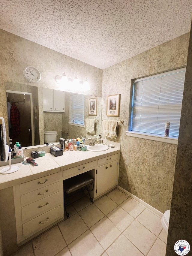 bathroom with baseboards, toilet, a textured ceiling, vanity, and tile patterned floors