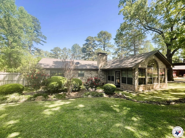 rear view of house with brick siding, fence, a lawn, and a chimney