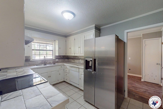 kitchen with white dishwasher, stainless steel fridge, a sink, tile counters, and ornamental molding