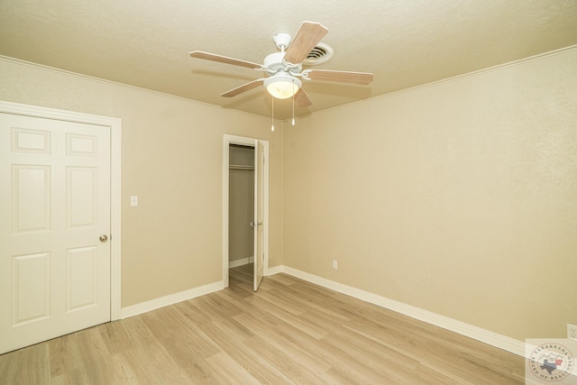 unfurnished bedroom featuring crown molding, light hardwood / wood-style flooring, a closet, and ceiling fan