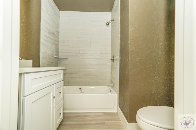 bathroom with tiled shower / bath combo, hardwood / wood-style floors, and toilet