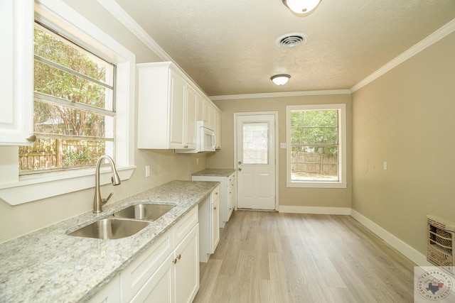 kitchen featuring light stone countertops, sink, white cabinets, and light hardwood / wood-style floors