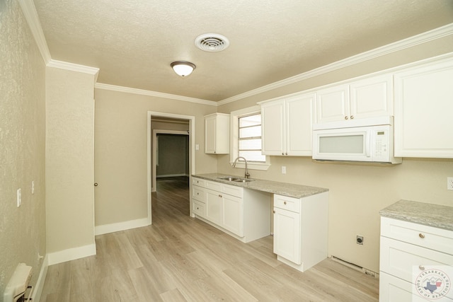 kitchen with crown molding, sink, white cabinetry, a textured ceiling, and light hardwood / wood-style floors