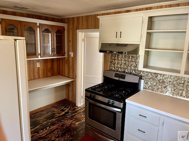 kitchen with white cabinets, white refrigerator, wood walls, stainless steel range with gas cooktop, and range hood