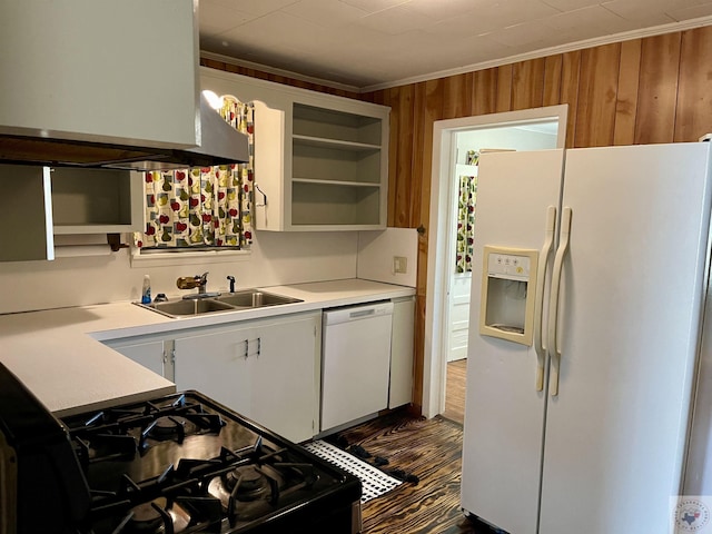 kitchen with white appliances, white cabinetry, sink, wood walls, and crown molding