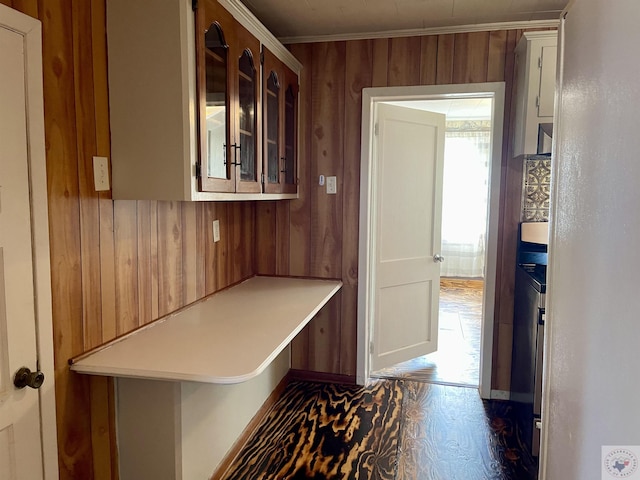 hallway featuring dark hardwood / wood-style flooring, crown molding, and wooden walls