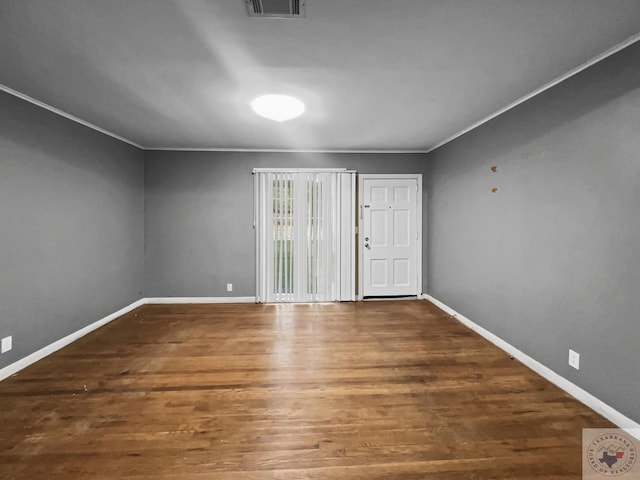 empty room featuring dark wood-type flooring and crown molding