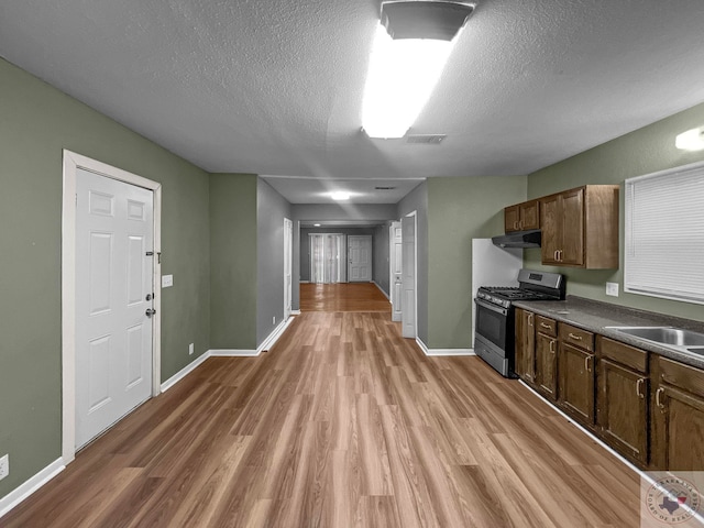 kitchen featuring light hardwood / wood-style floors, a textured ceiling, and stainless steel gas stove