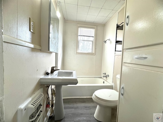 bathroom featuring washtub / shower combination, hardwood / wood-style floors, and toilet