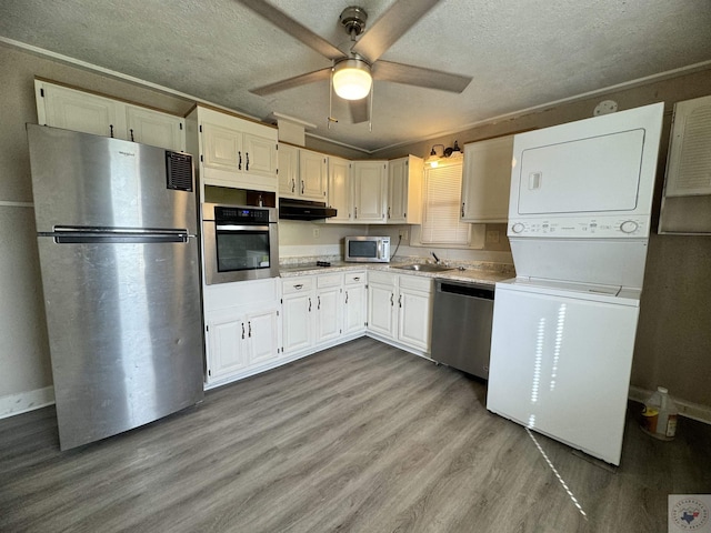 kitchen featuring sink, white cabinets, appliances with stainless steel finishes, and stacked washing maching and dryer