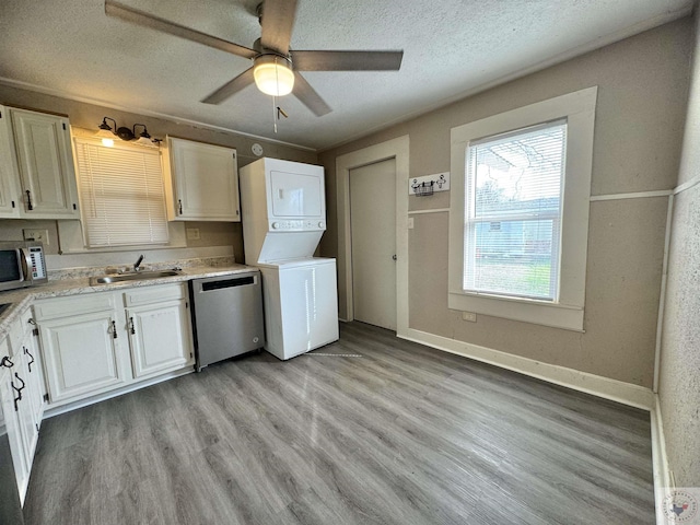 kitchen featuring sink, stacked washer / dryer, white cabinets, and stainless steel appliances