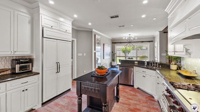 6914 Manor Crest Dr, Texarkana, AR 71854 - kitchen with stainless steel appliances, brick floors, a sink, white cabinetry, and recessed lighting