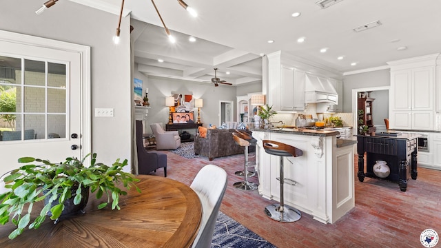 6914 Manor Crest Dr, Texarkana, AR 71854 - kitchen with ceiling fan, white cabinetry, open floor plan, premium range hood, and a breakfast bar