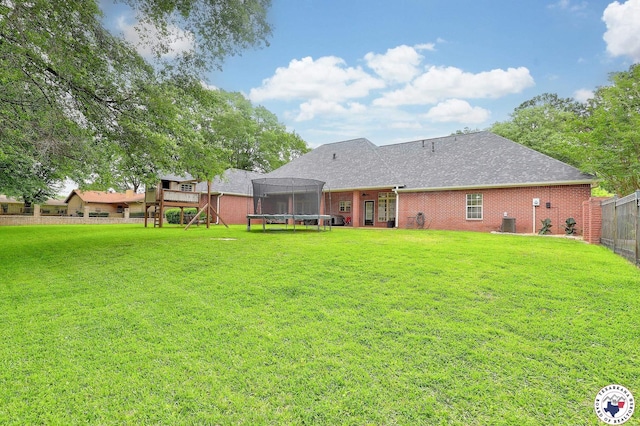 16 Bill Rogers Dr, Texarkana, TX 75503 - back of property with a trampoline, brick siding, cooling unit, and roof with shingles