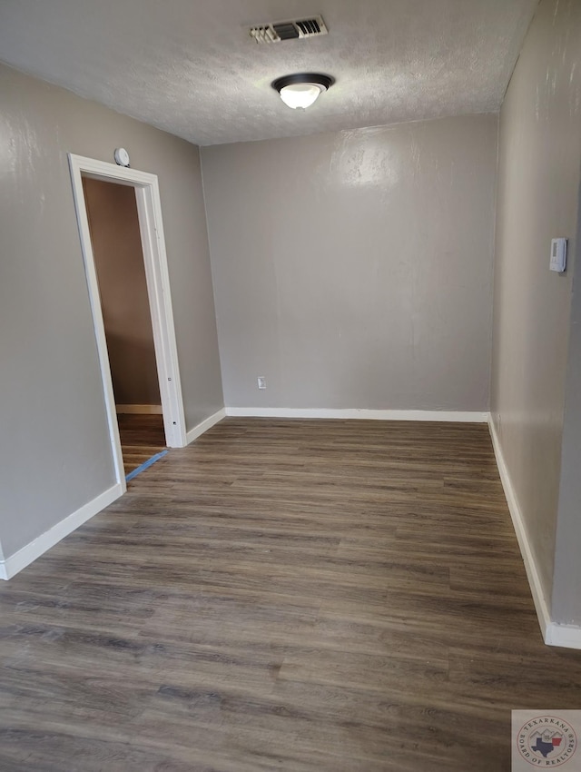 empty room with a textured ceiling and dark hardwood / wood-style floors