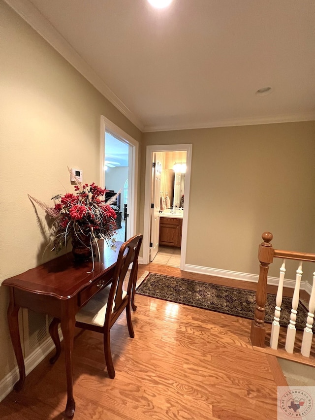 corridor with light wood-type flooring and crown molding