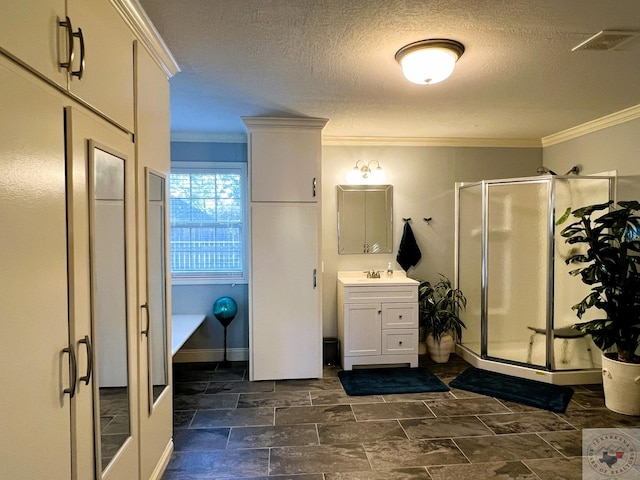 bathroom featuring vanity, ornamental molding, a shower with door, and a textured ceiling