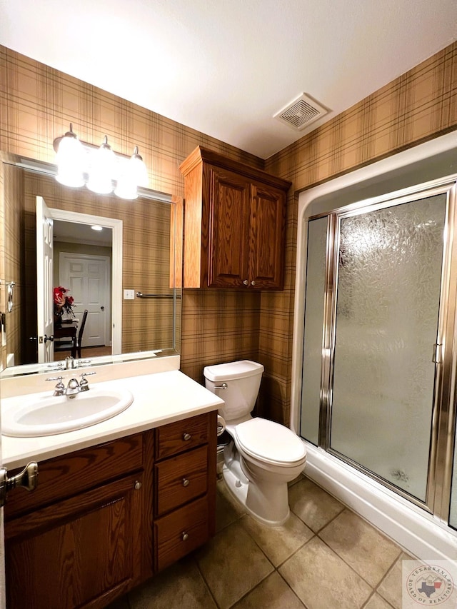 bathroom featuring a shower with shower door, toilet, vanity, and tile patterned flooring