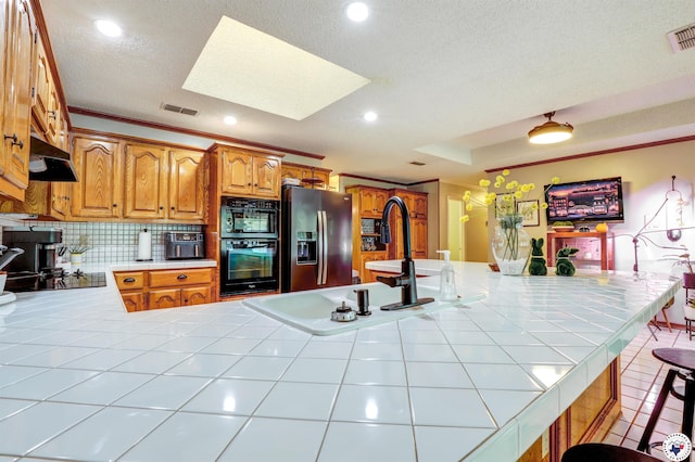 3502 Tiffany Ln, Texarkana, AR 71854 - kitchen with black appliances, a skylight, under cabinet range hood, tasteful backsplash, and tile counters