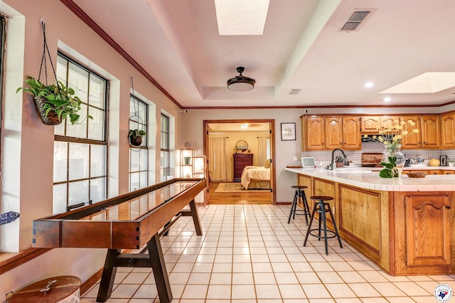 3502 Tiffany Ln, Texarkana, AR 71854 - kitchen featuring a raised ceiling, tasteful backsplash, ornamental molding, a breakfast bar, and a sink