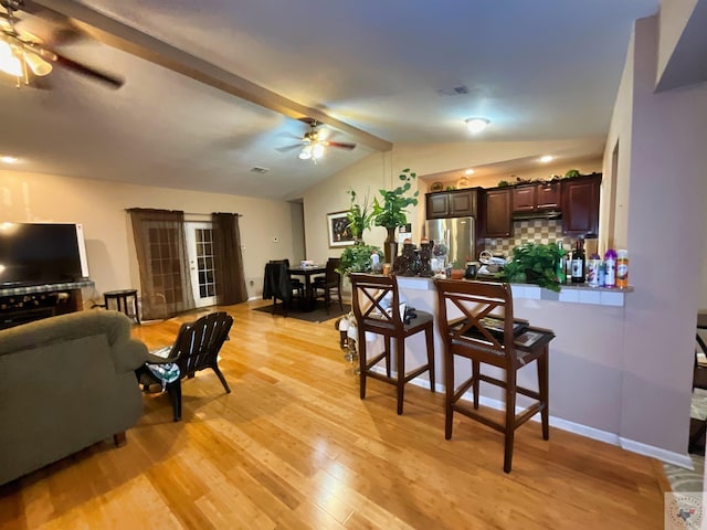 living room with ceiling fan, light hardwood / wood-style flooring, and lofted ceiling with beams