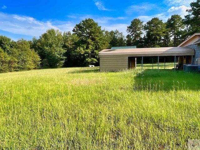 view of yard featuring central AC unit and a carport