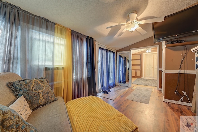 bedroom with ceiling fan, wood-type flooring, lofted ceiling, and a textured ceiling