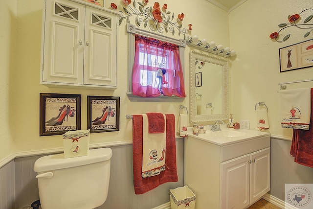 bathroom with toilet, vanity, and ornamental molding