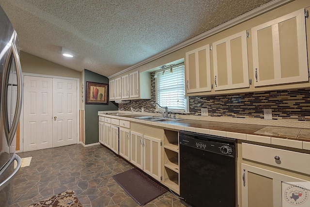 kitchen with dishwasher, lofted ceiling, tile counters, sink, and stainless steel fridge