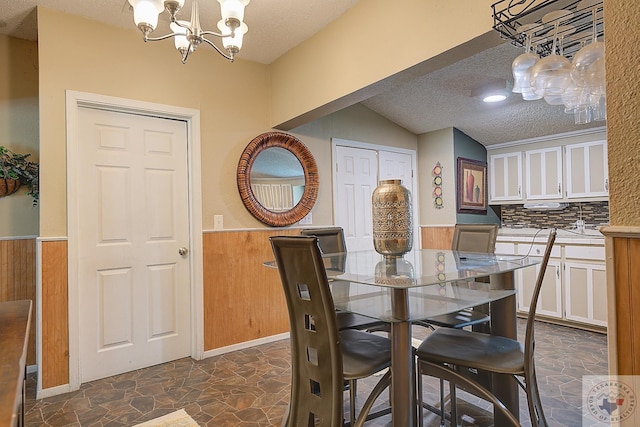 dining room featuring an inviting chandelier, a textured ceiling, and lofted ceiling