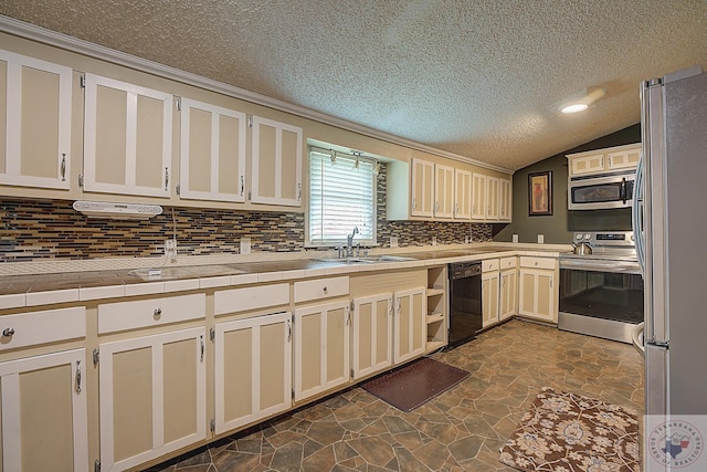 kitchen featuring appliances with stainless steel finishes, a textured ceiling, sink, vaulted ceiling, and tile countertops