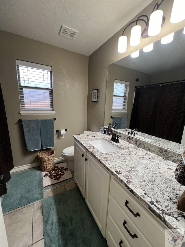 bathroom featuring a textured ceiling, tile patterned floors, a wealth of natural light, and vanity