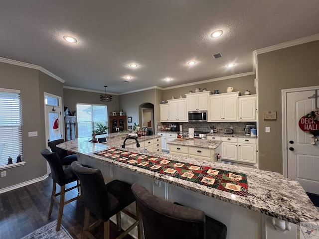 kitchen featuring white cabinetry, a breakfast bar, a spacious island, and appliances with stainless steel finishes