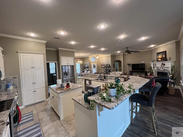 kitchen featuring light stone countertops, a textured ceiling, white cabinets, a kitchen island, and stainless steel appliances