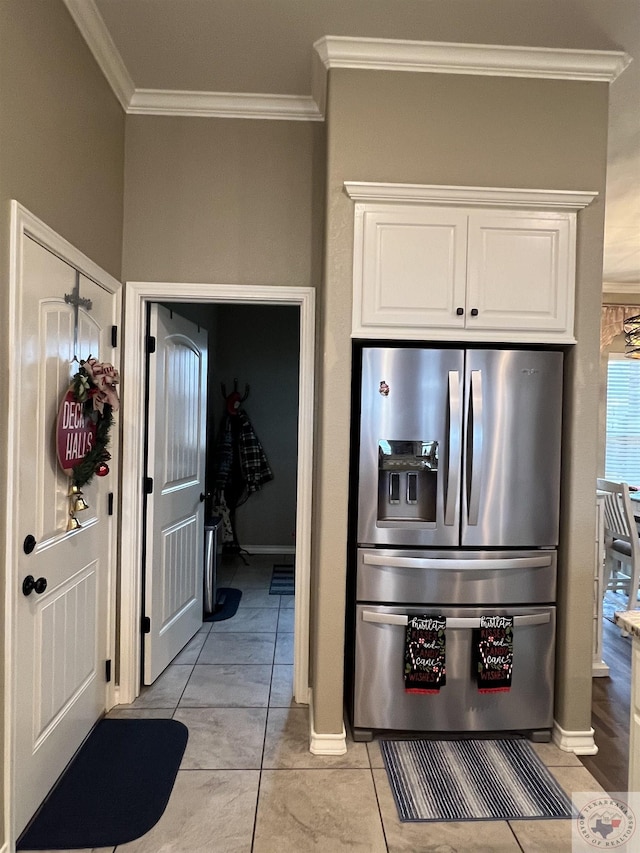 kitchen with stainless steel refrigerator with ice dispenser, white cabinetry, light tile patterned floors, and crown molding